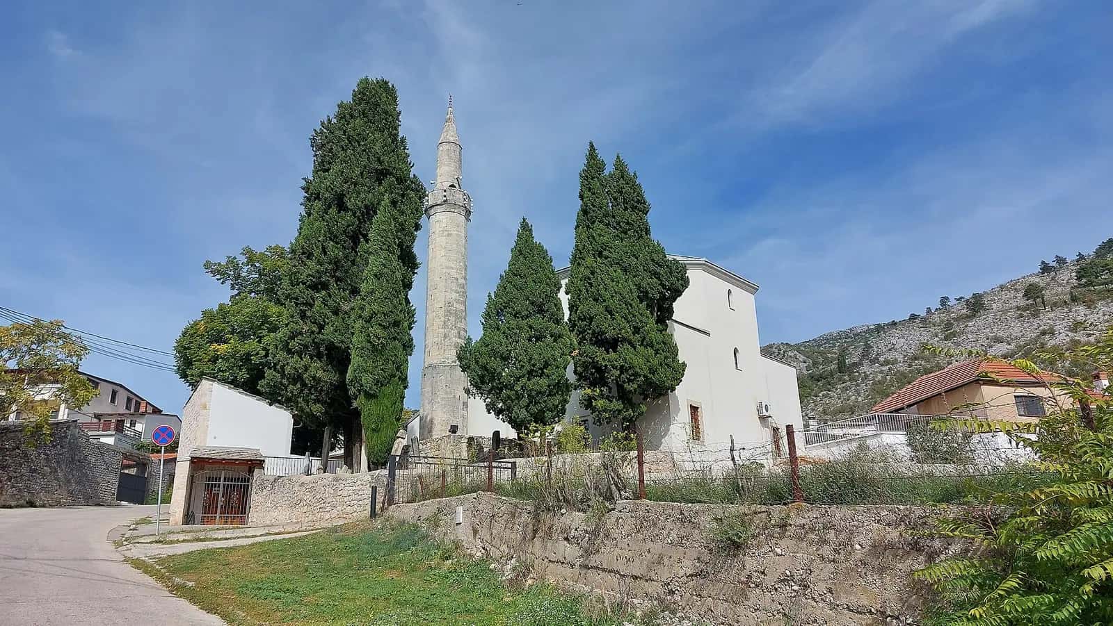 Blagay'daki Sultan Süleyman Camii'nin beyaz duvarları, taş minaresi ve servi ağaçları