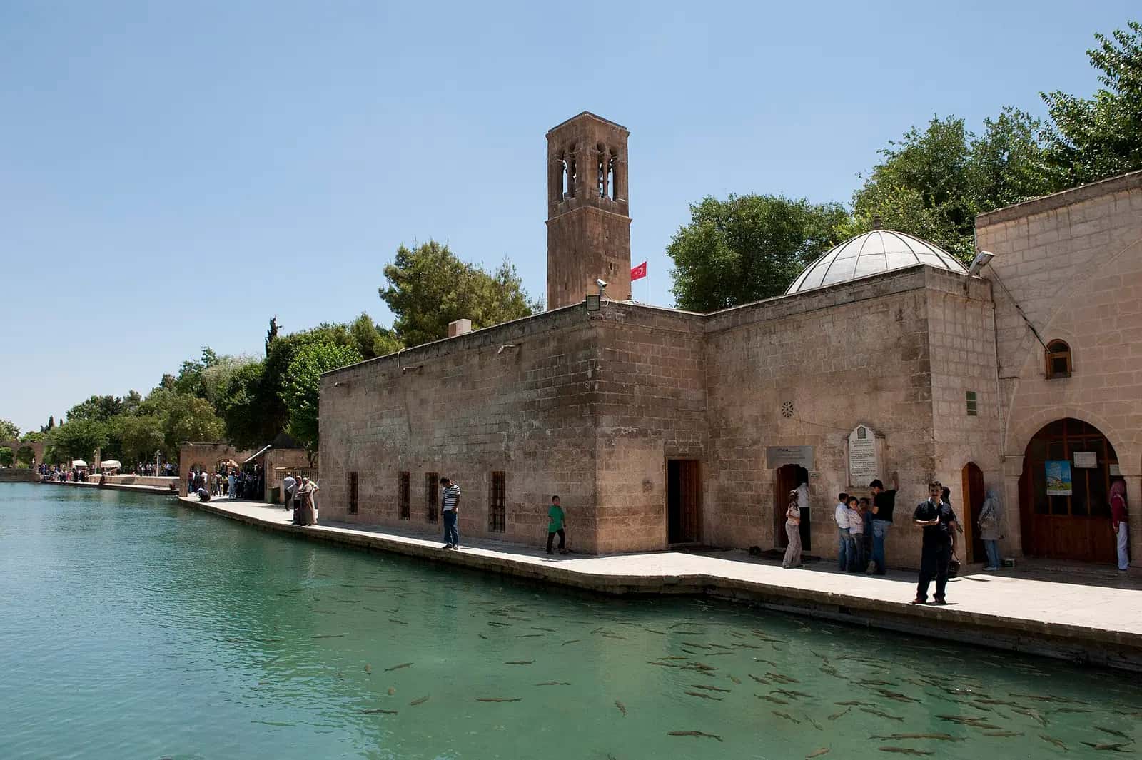 Balıklıgöl kıyısında Halilürrahman Camii'nin taş duvarları ve kare gövdeli minaresi