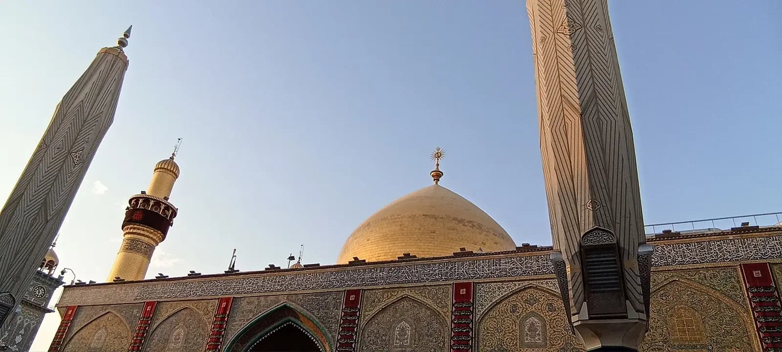 Sabah ışığında Necef'teki İmam Ali Türbesi'nin altın kubbesi ve minareleri.