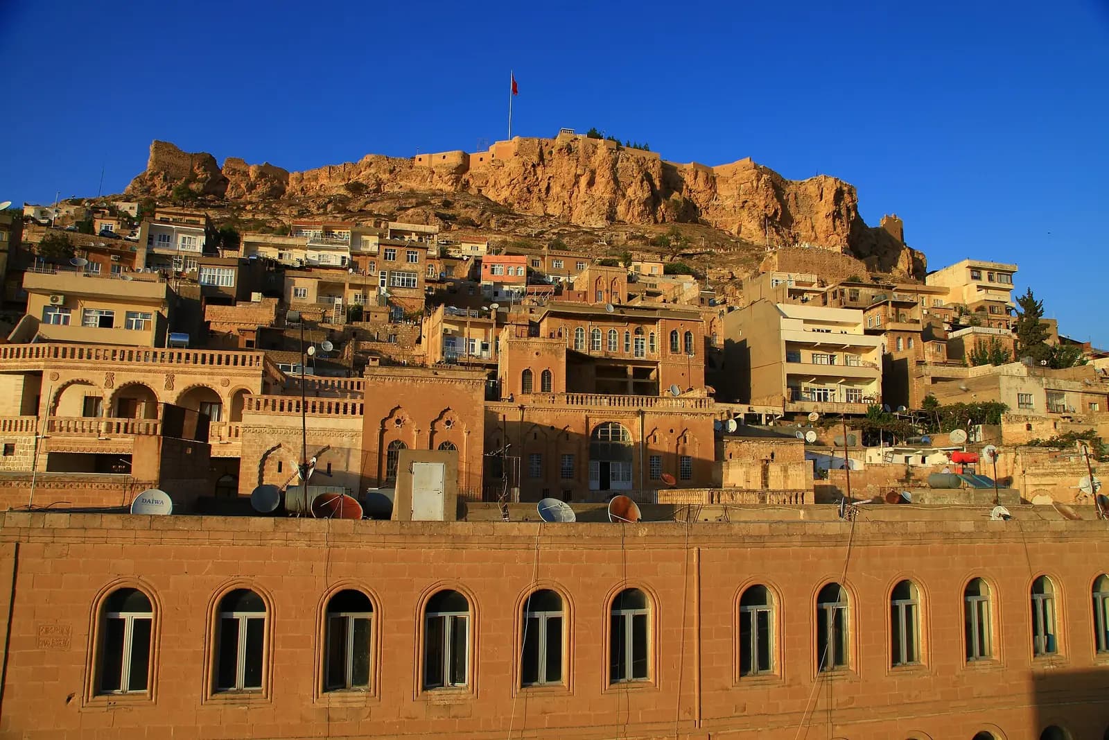 Kalenin altında yamaç boyunca basamaklanan Mardin'in taş evleri