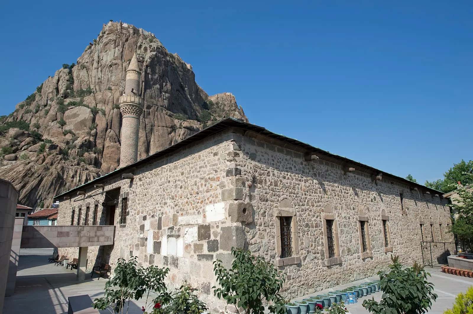 Afyon Ulu Camii'nin taş gövdesi, minaresi ve arkasında kale kayalığı