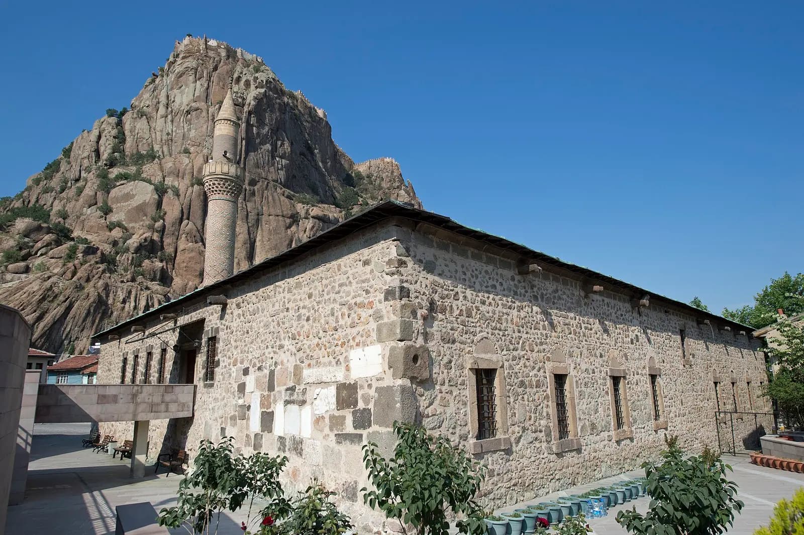Afyon Ulu Camii'nin taş gövdesi, minaresi ve arkasında kale kayalığı