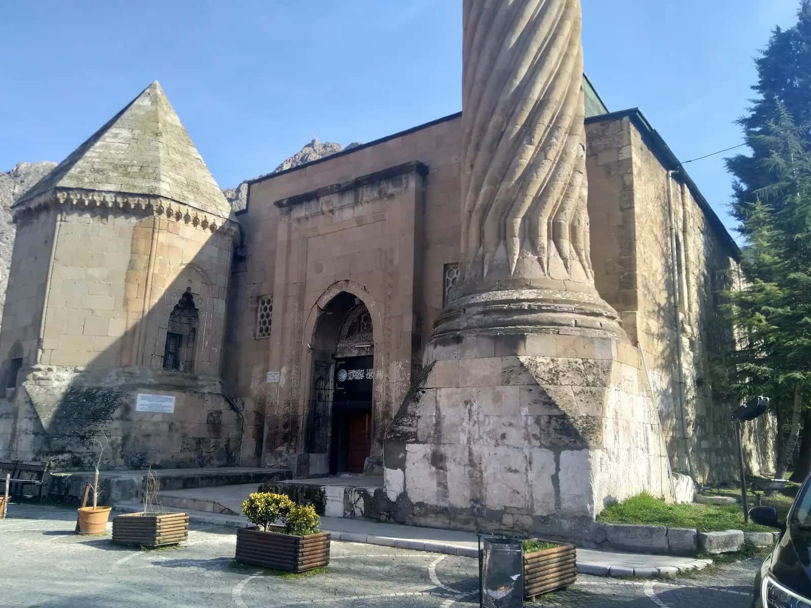 Burmalı Minare Camii'nin sarmal yivli taş minaresi, taç kapısı ve yanındaki türbe