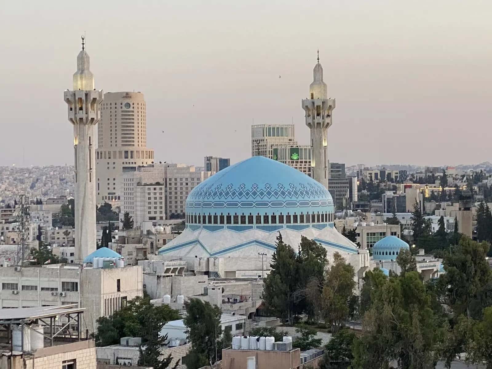 Kral Abdullah Camii'nin mavi mozaik kubbesi ve iki minaresi, arkada Amman binaları