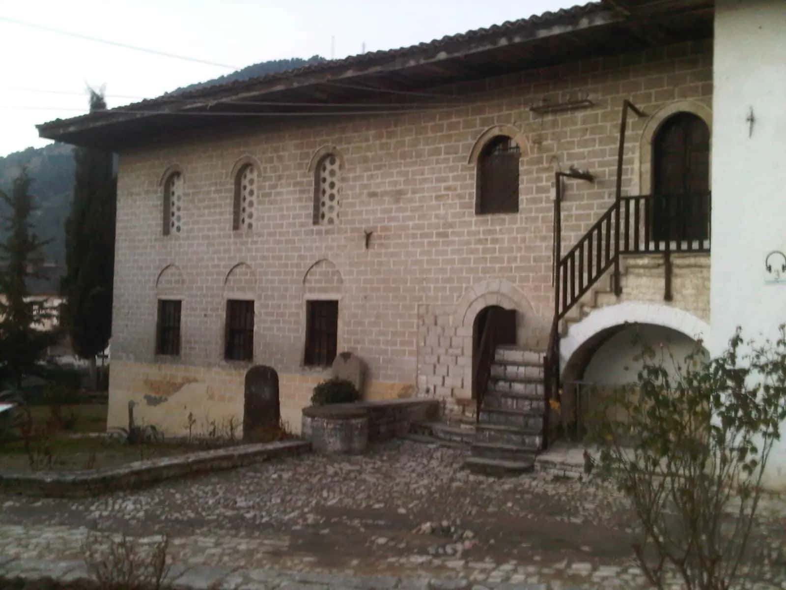 Berat'taki Kral Camii'nin kırma çatılı taş gövdesi ve önündeki taş döşeli avlu