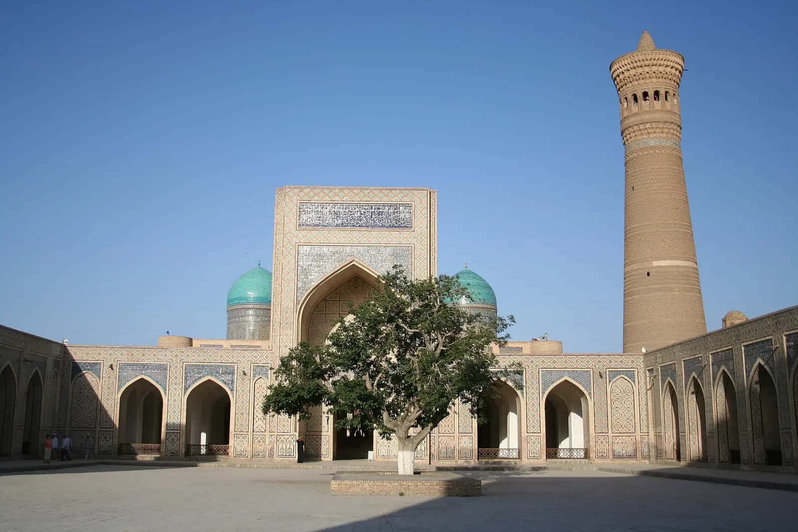Kalon Minaresi'nin süslü tuğla gövdesi ve yanındaki Kalon Camii'nin kubbesi