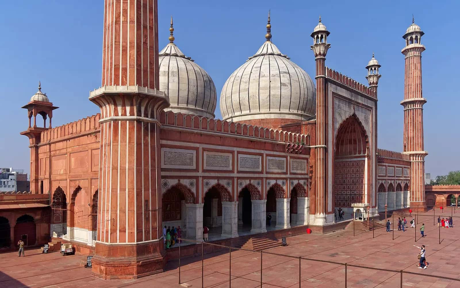 Delhi Cuma Mescidi'nin kırmızı kumtaşı ve beyaz mermer şeritli minaresi ile mermer kubbeleri