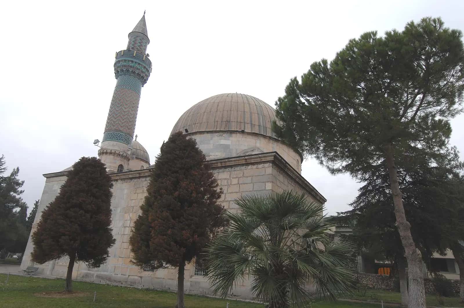 İznik Yeşil Camii'nin mermer kaplı cephesi ve minaresinin yakındaki parktan görünümü.
