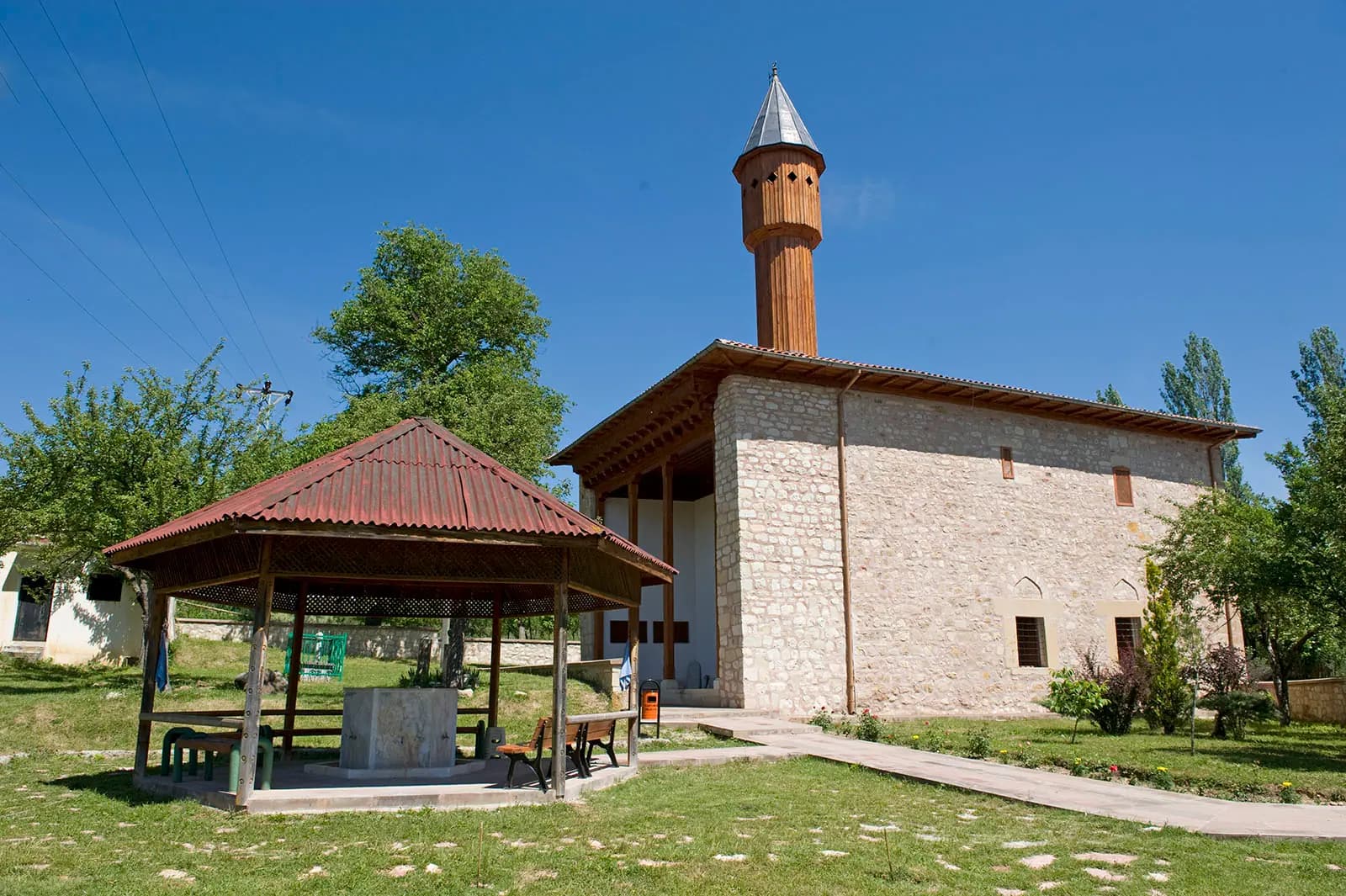 Kasabaköy'deki Mahmut Bey Camii'nin taş gövdesi, ahşap saçağı ve minaresi