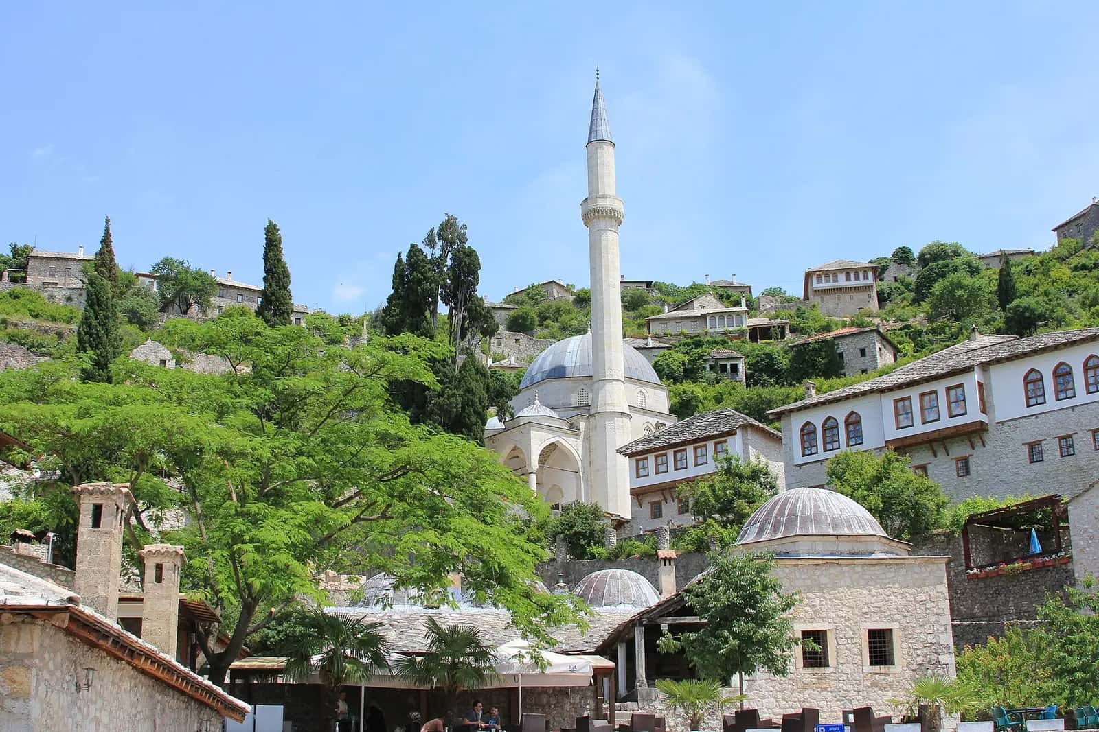 Počitelj'deki Hacı Alija Camii'nin kubbesi ve minaresi, çevresindeki taş evler ve yeşillik
