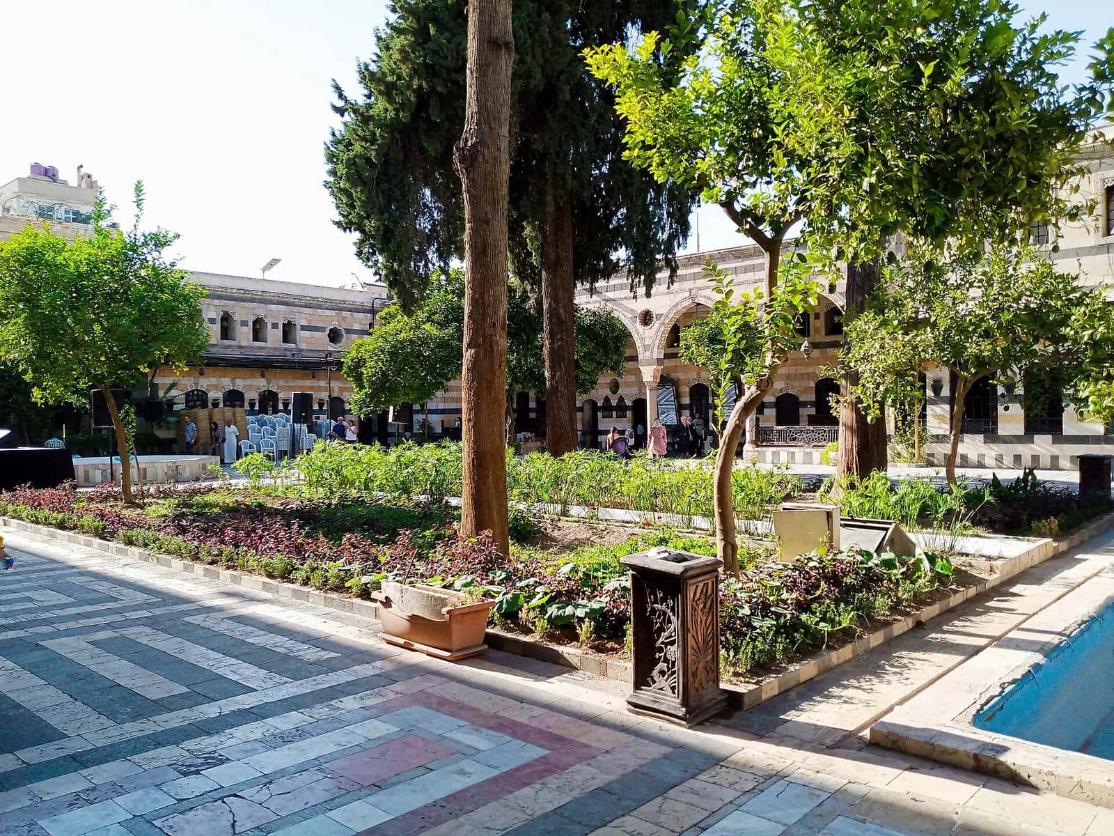 Azm Sarayı'nın ağaçlı ve çiçekli avlusu, ablak taşlı cepheleri