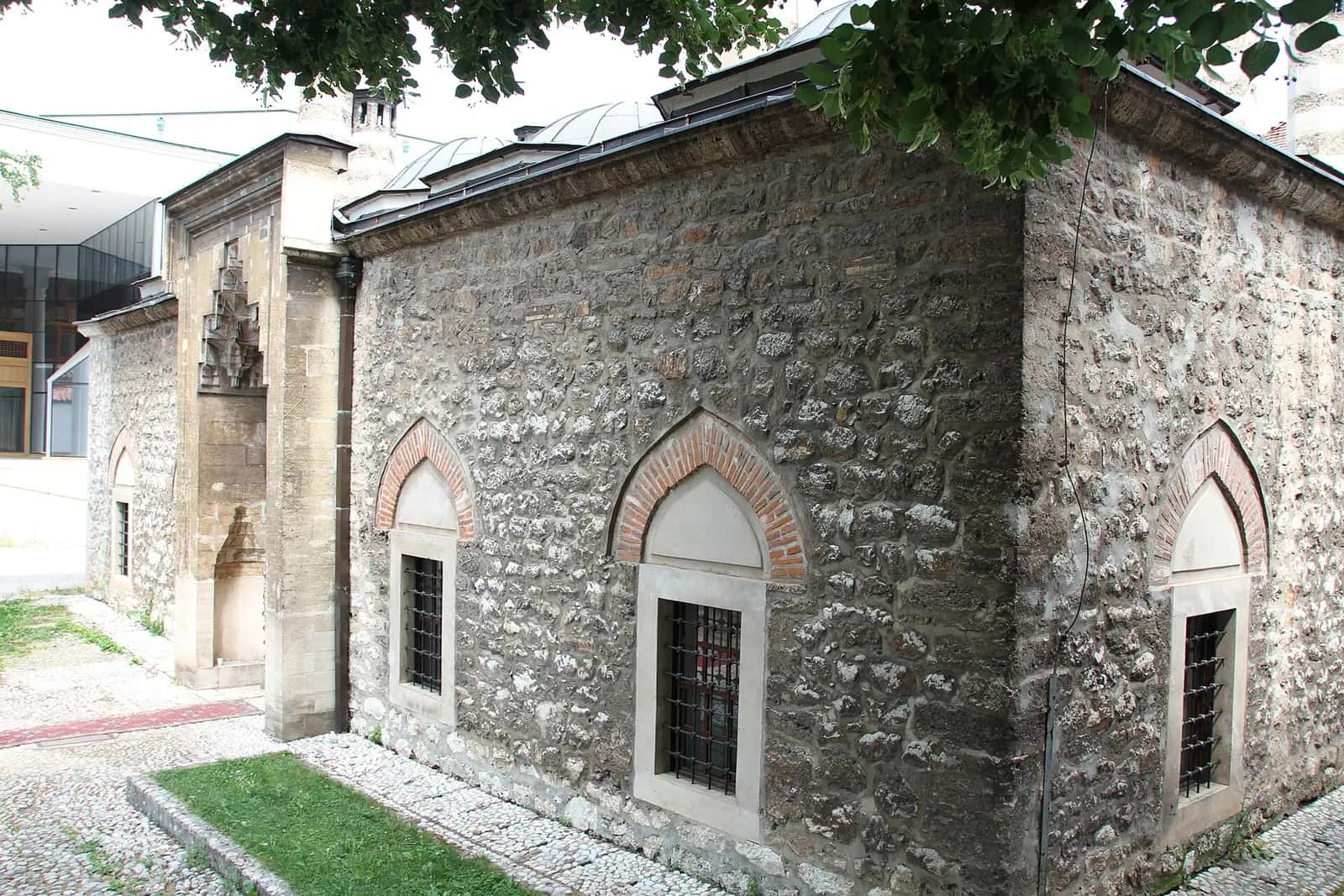Gazi Hüsrev Bey Medresesi'nin kesme taş duvarları, kemerli pencereleri ve kurşun kaplı kubbeleri