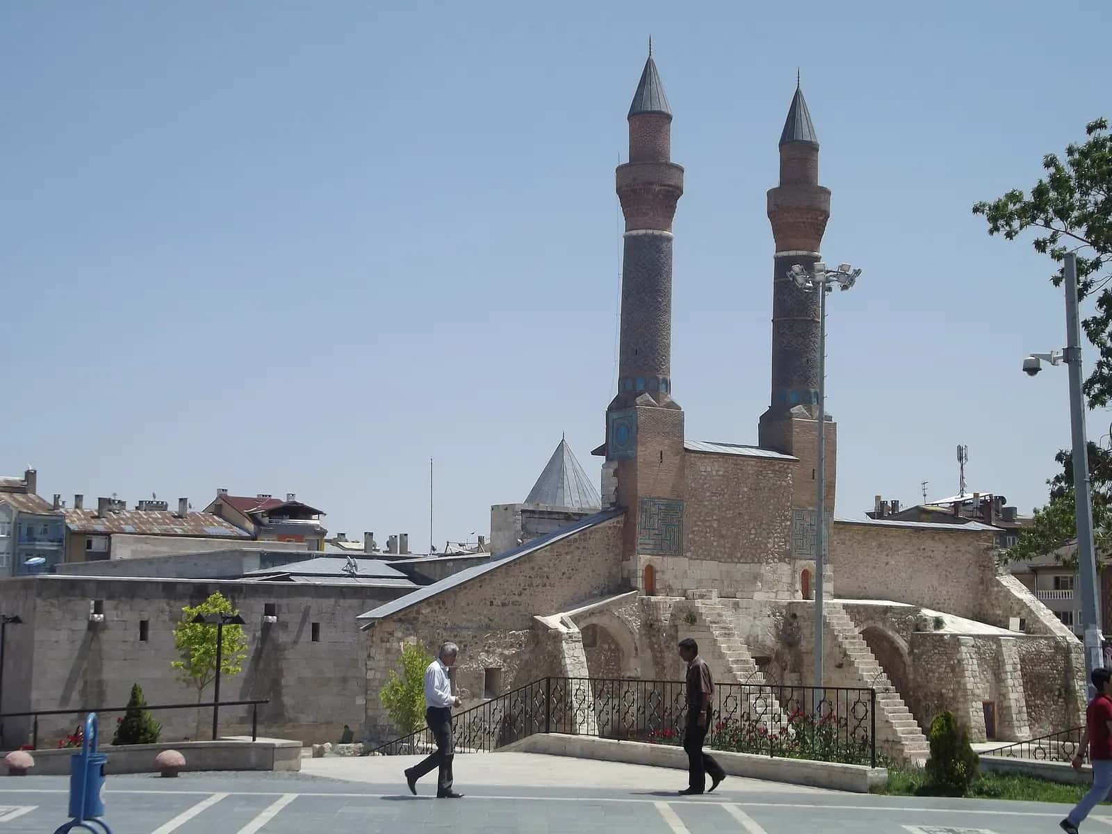 Çifte Minareli Medrese'nin iki tuğla minaresi ve taç kapılı ön cephesi