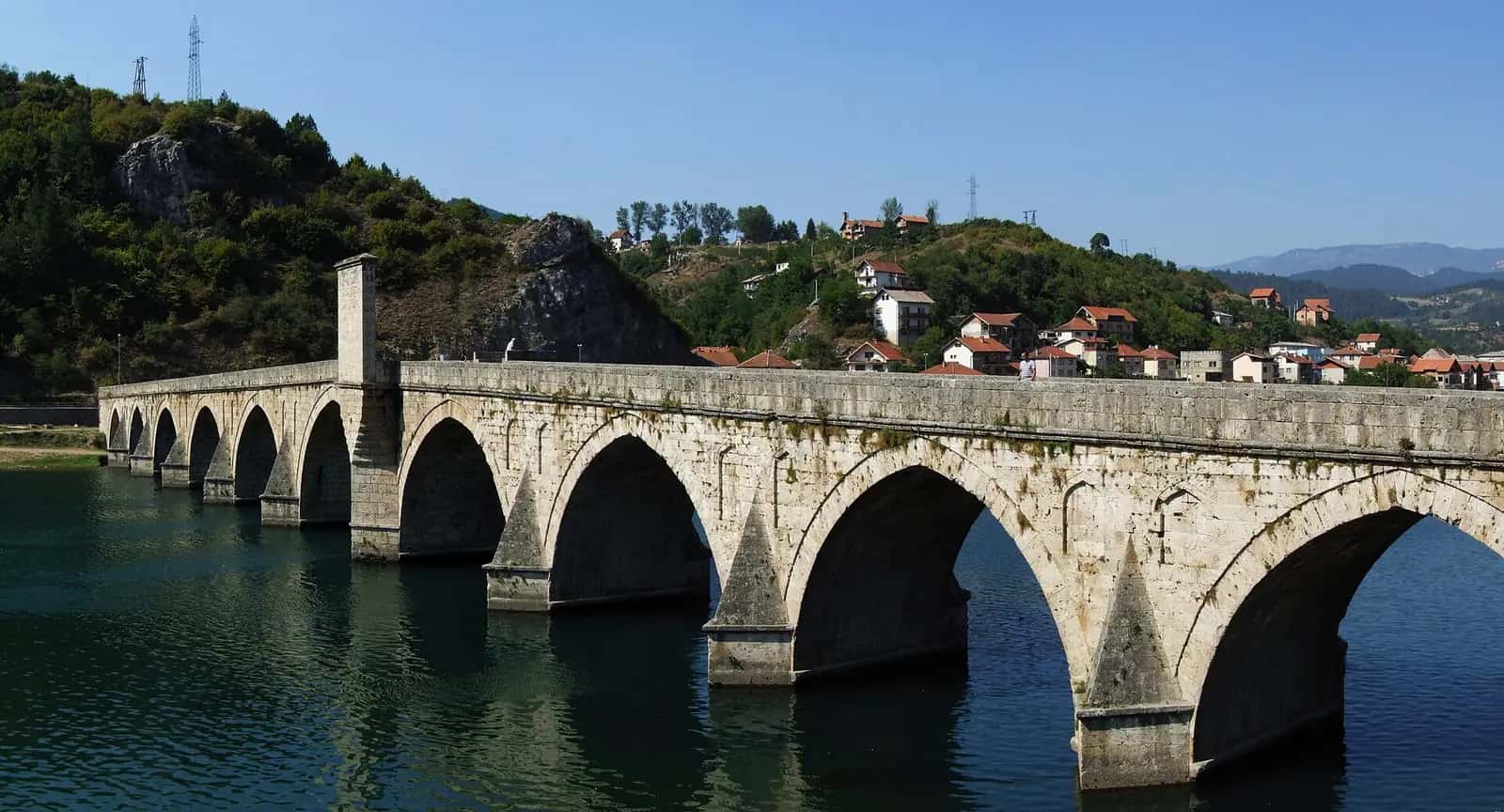 Drina nehri üzerindeki çok kemerli Sokullu Mehmed Paşa Köprüsü ve arkasındaki yeşil tepeler